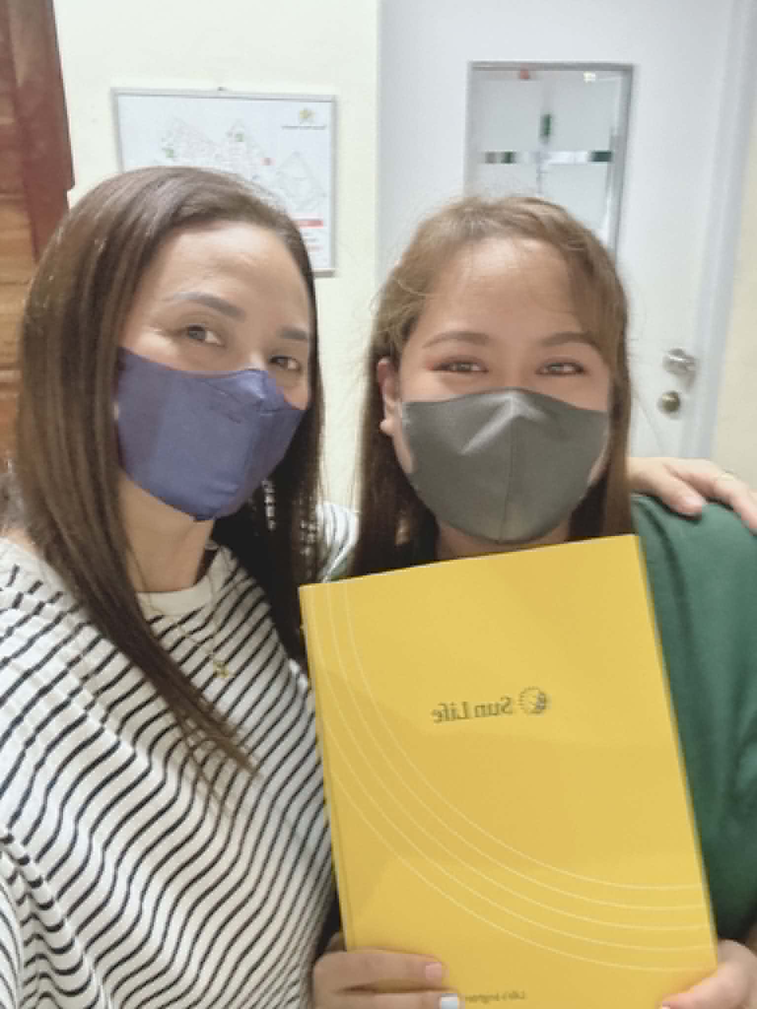 Ruth Abestilla with a client holding her new yellow Sun Life policy folder